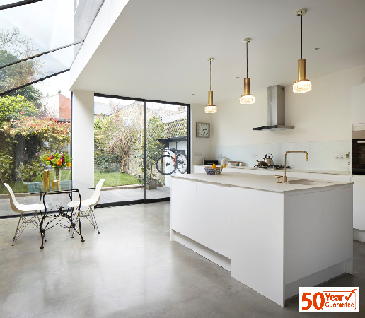 modern kitchen / living space with kitchen unit, table and chairs, polished concrete floor and 50 year guarantee logo