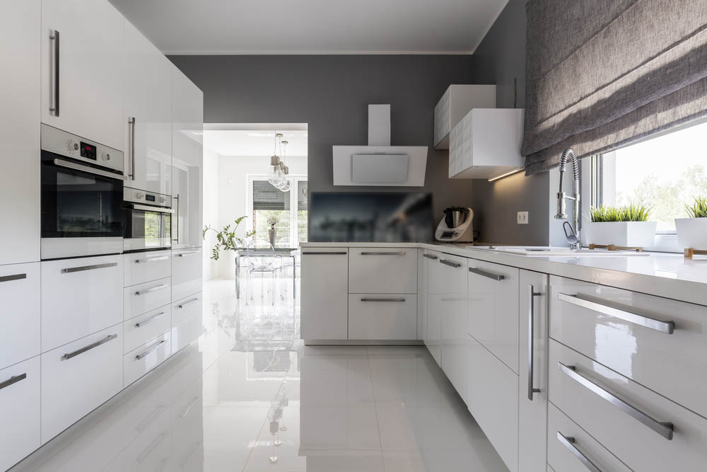 Modern kitche with grey walls, white units and pale grey tiled floor